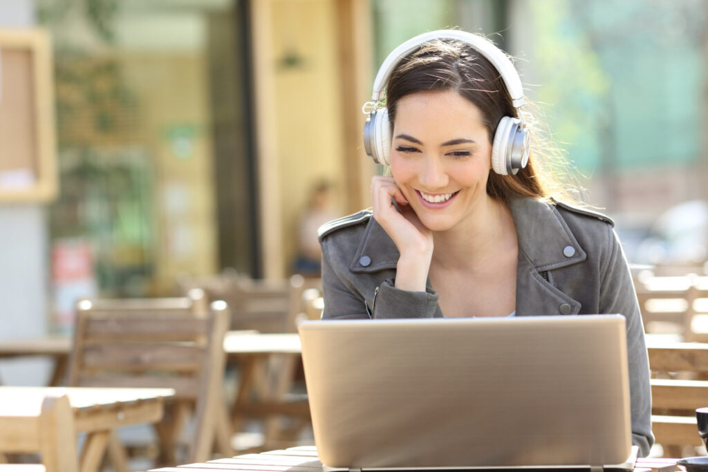 海外就職準備のため、カフェでヘッドフォンを着用して語学力を磨く女性