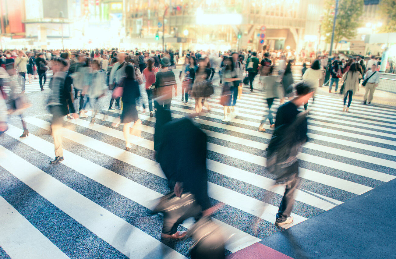 人生100年時代における、キャリアの中間地点を象徴する交差点を渡る人々